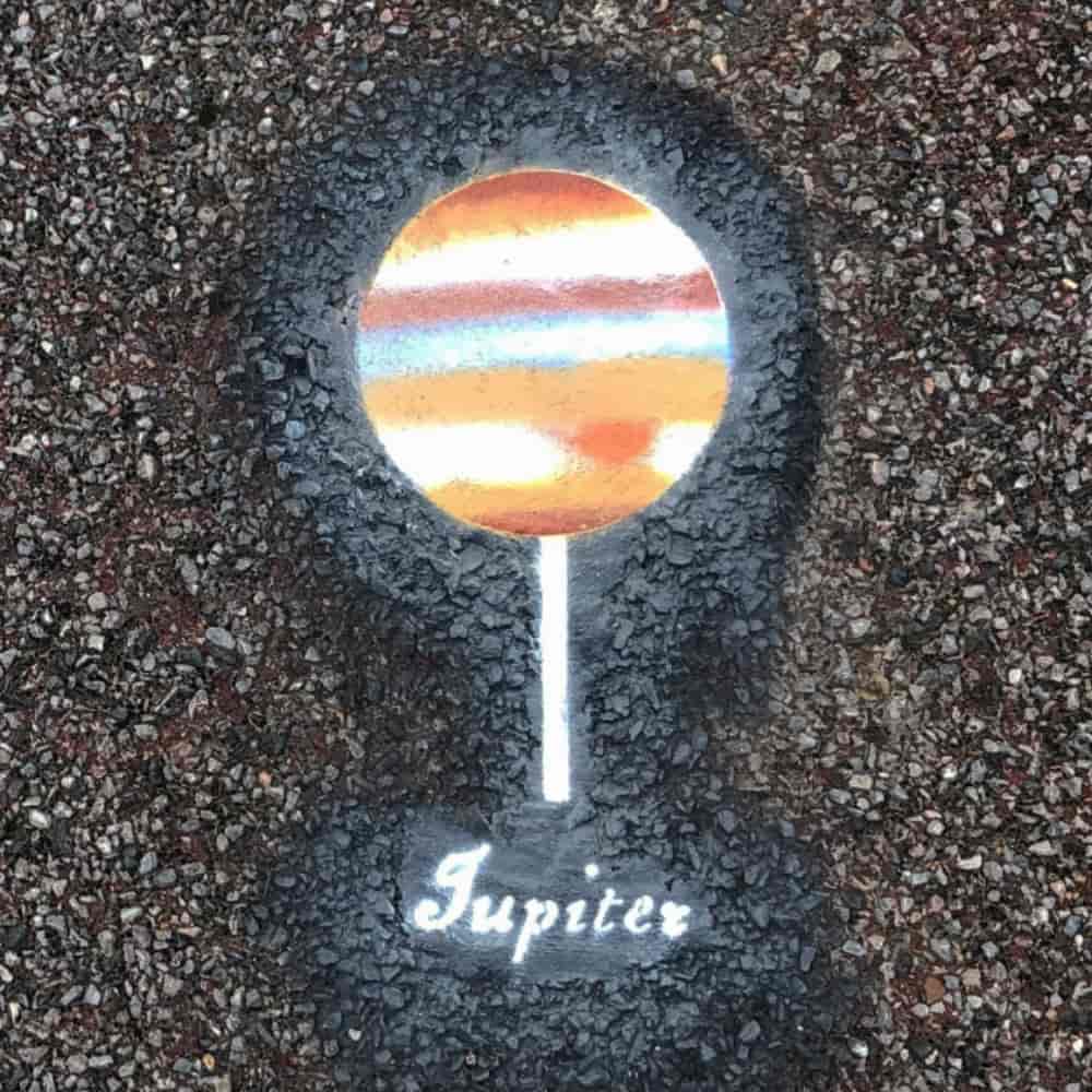 Planet Jupiter, 14 cm in diameter, painted on the pavement with a name tag.
