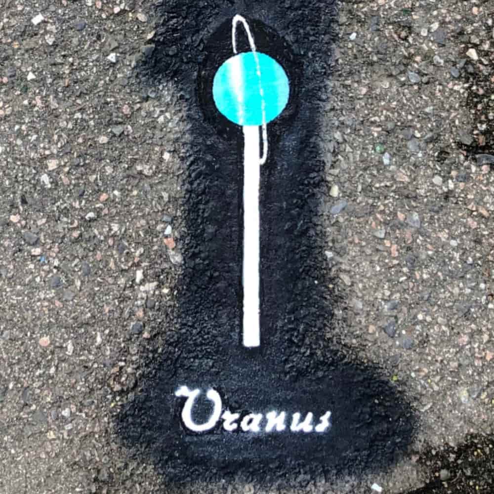 Planet Uranus, 5 cm in diameter, painted on the pavement with a name tag.
