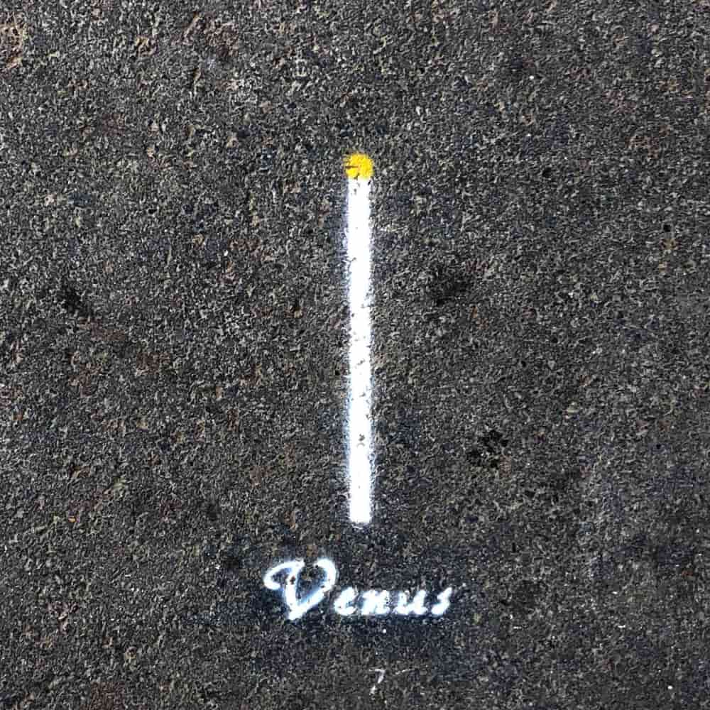 Planet Venus, 1.2 cm in diameter, painted on the pavement with a name tag.